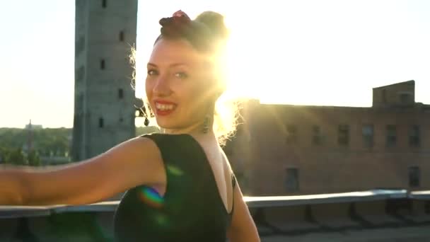 portrait of young woman looking at camera and dancing on roof at sunset - Imágenes, Vídeo