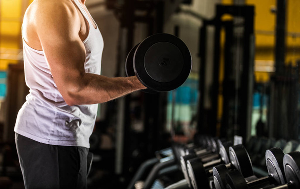 Closeup of young fitness trainer with dumbbells - Photo, Image