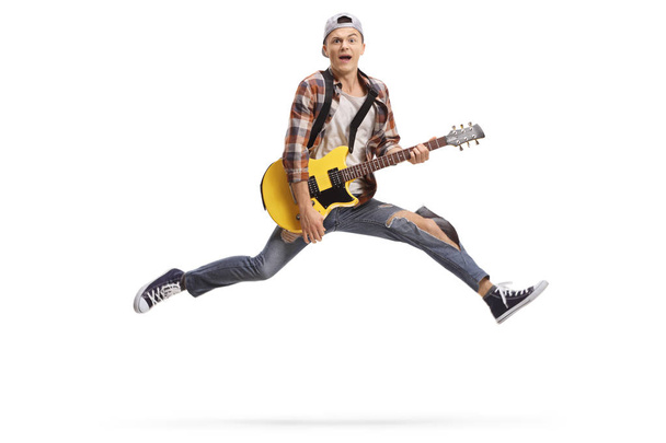 Young male musician playing an electric guitar and jumping - Foto, afbeelding