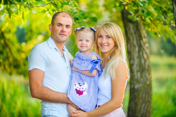 Happy family in a beautiful spring park, hugging standing against the backdrop of bright foliage - Valokuva, kuva