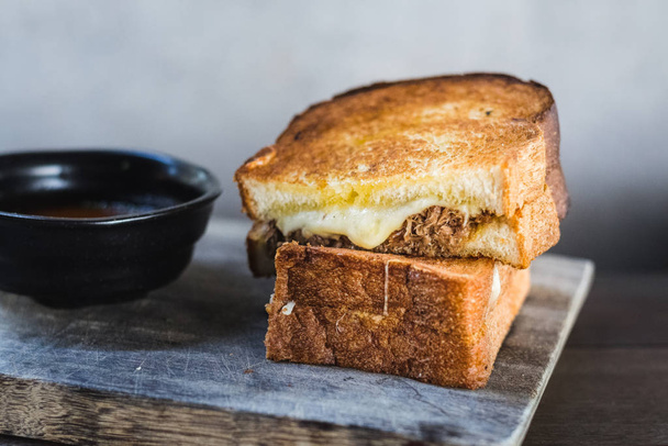 Braised Shortrib Grilled Cheese.  A blend of gruyere and taleggio cheese sandwiched between buttery artisanal white loaves.  Stuffed with juicy, braised beef shortrib. - Photo, Image