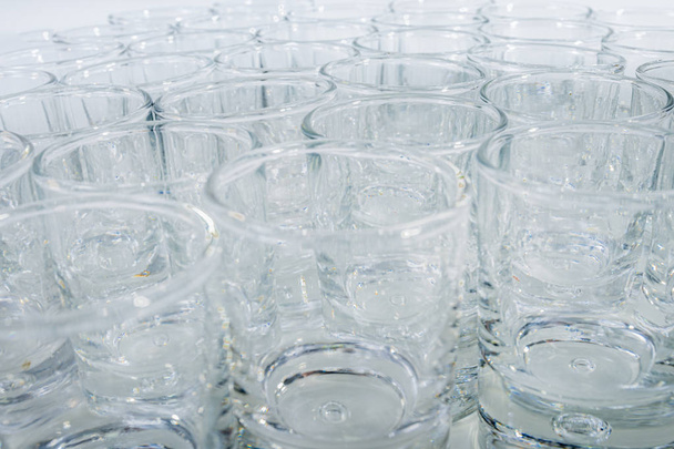 Close-up of many glass cups on a white background - Luxurious, shiny cups - Fotó, kép