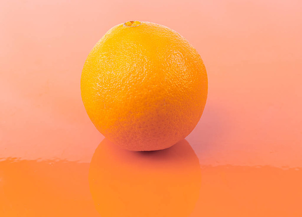 Una naranja madura sobre un fondo naranja - Naranja recién cosechada
 - Foto, imagen