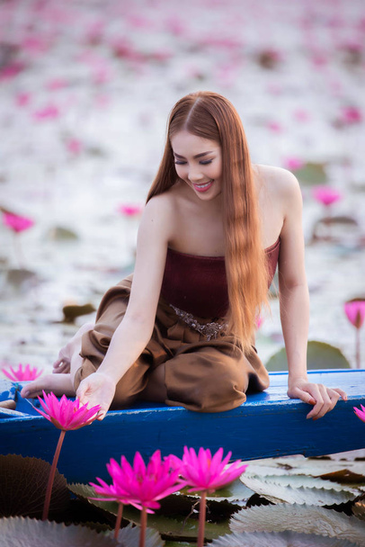 16. März 2019, udon thani thailand, wunderschönes thailändisches mädchen sitzt glücklich auf einem boot im roten lotusteich, roter lotussee in udon thani schöner naturteich - Foto, Bild
