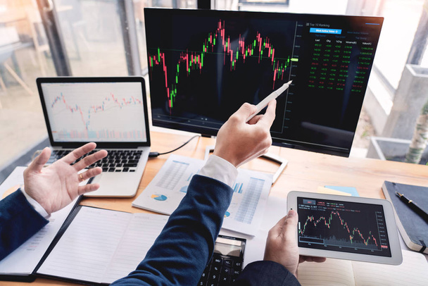株式ブローカーのチーム ディスプレイ画面で議論投資のための株式市場取引のデータ、グラフやレポートを分析  - 写真・画像