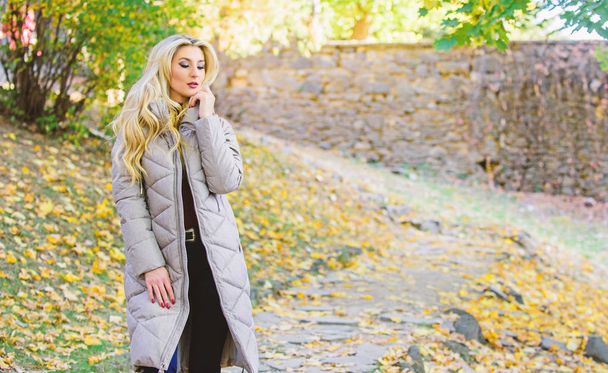 Puffer jacket casual and comfortable style. Girl fashionable blonde walk in autumn park. Woman wear warm grey jacket. Jacket everyone should have. Puffer fashion trend concept. Oversized jacket trend - Zdjęcie, obraz