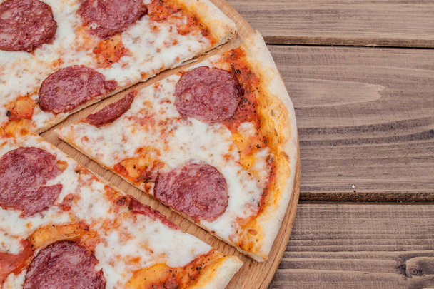 Italian Pepperoni pizza with salami on dark wooden background top view. Italian traditional food. Popular street food - Photo, Image