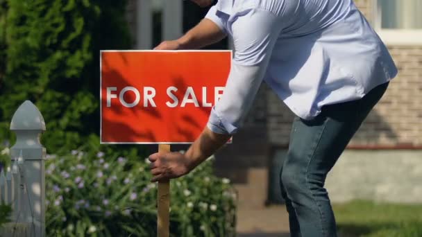 House owner setting for sale sign front of house, real estate agency, relocation - Materiał filmowy, wideo