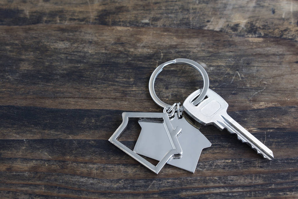 Κλειδί και σπίτι κρεμαστό κόσμημα σε ένα ρουστίκ ξύλινο φόντο - Φωτογραφία, εικόνα