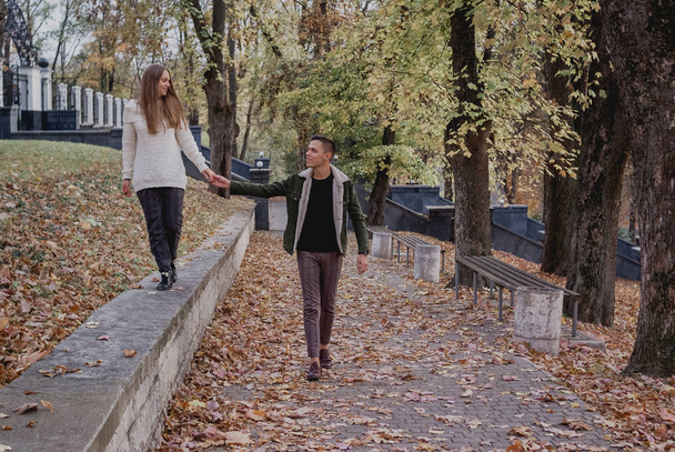 Ευτυχισμένο νεαρό ζευγάρι που περπατάει μια φθινοπωρινή μέρα στο πάρκο. Διασκεδάζουν μαζί. χαριτωμένος έφηβος - Φωτογραφία, εικόνα