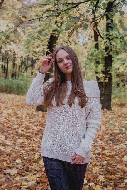 Close up portrait of a Beautiful girl in white sweater near colorful autumn leaves. Artwork of romantic woman .Pretty tenderness model smiling - Fotografie, Obrázek