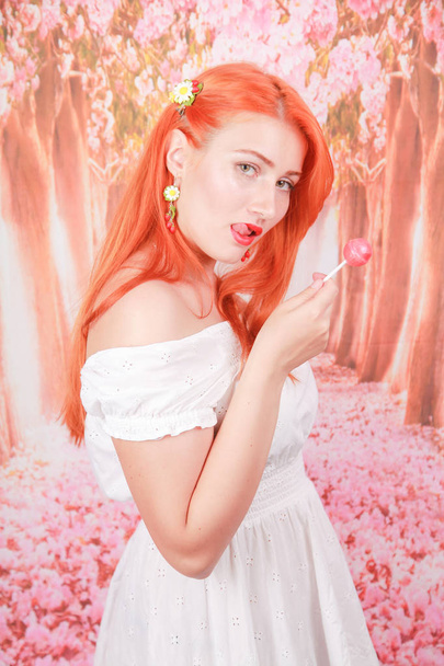 Здивована сексуальна дівчина їсть льодяник. Краса Гламур Модель жінка з помаранчевим волоссям тримає рожеві цукерки
 - Фото, зображення
