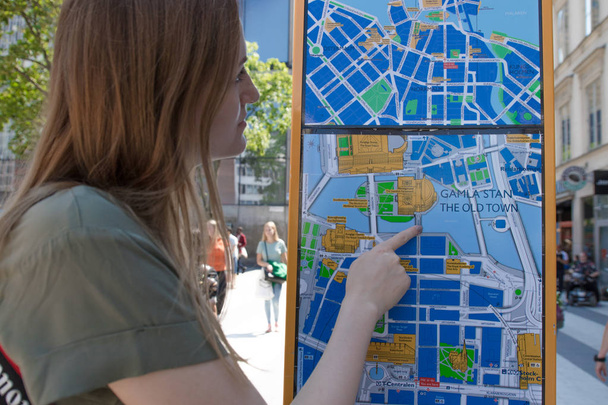 Young blonde girl orientating herself on the public map. - Foto, afbeelding