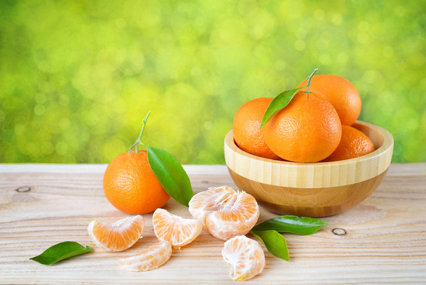 Mandarino con foglie in un piatto di legno su un tavolo di legno
. - Foto, immagini