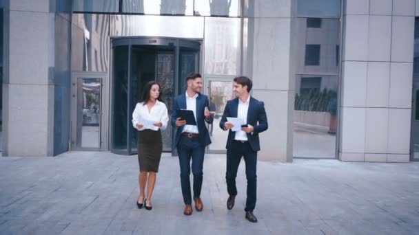 Başarılı İş Adamları İş Tartışmak ve Central Business District yürümek. İki Genç Erkek ve Takım Elbiseli Bir Kadın İletişim ve İş Merkezi Ofis Binası yakınında yürümek. - Video, Çekim