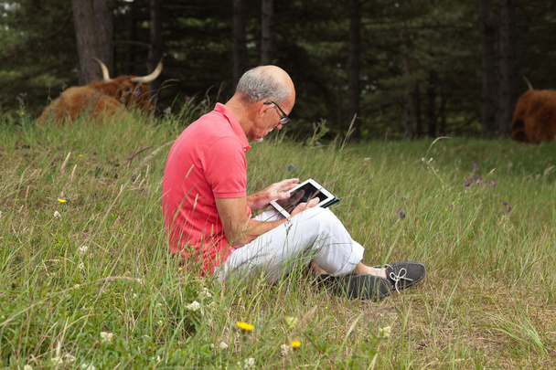 シニア タブレットの牧草地で屋外に座って男を引退しました。スコット - 写真・画像