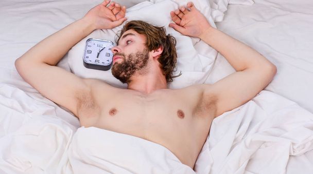 Man eyes are closed with relaxation. Cheerful young man is waking up after sleeping in the morning. Top view of sexy muscular young man sleeping in bed. - Foto, Imagen