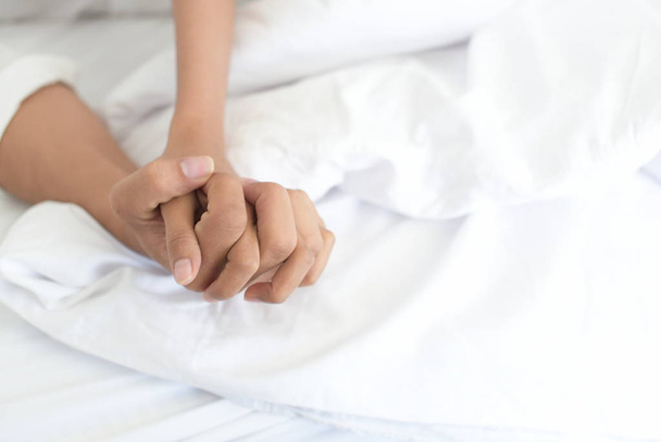 Nahaufnahme von zwei Händen im Bett - Foto, Bild