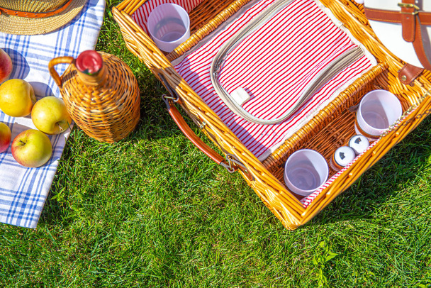 Conceito de piquenique com cesta no gramado ensolarado verde no parque
 - Foto, Imagem