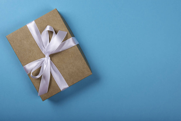 Gift box with bow on neon blue background. Space for text on the right side of the image. - Photo, Image