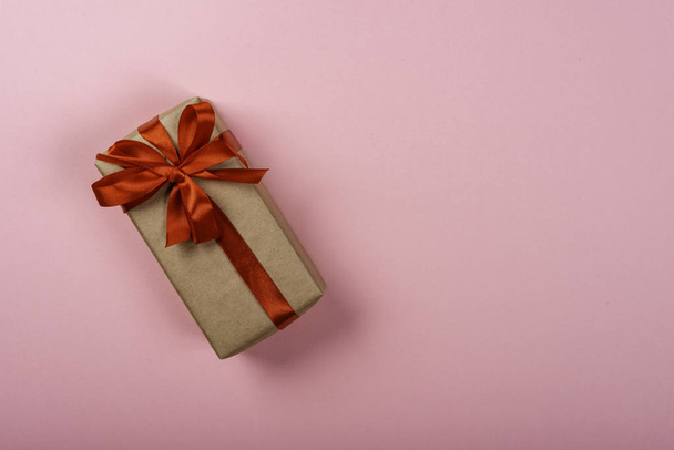 Κουτί δώρου με τόξο σε ροζ φόντο. Χώρος για κείμενο στη δεξιά πλευρά της εικόνας. - Φωτογραφία, εικόνα