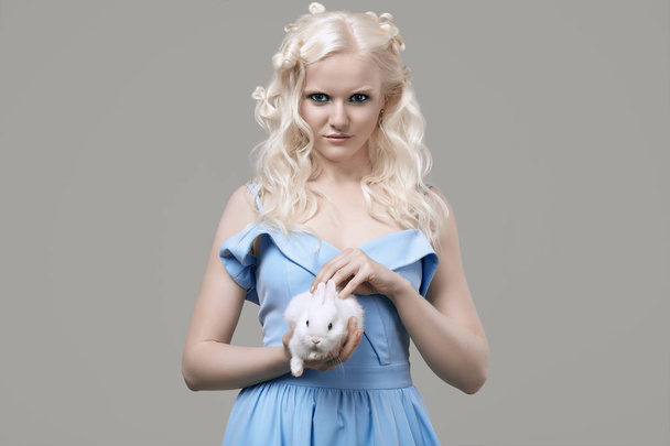 Albino blond meisje in elegante jurk poseren met schattige kleine konijn - Foto, afbeelding