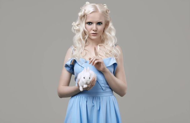 Albino blond girl in elegant dress posing with cute little rabbit - Foto, Imagen