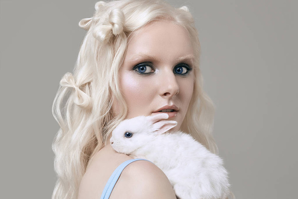 Albino blondes Mädchen in elegantem Kleid posiert mit niedlichem kleinen Kaninchen - Foto, Bild