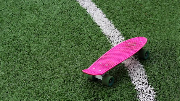 Pink skateboard on green grass - Фото, изображение