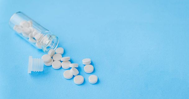 Witte pillen en glazen fles op blauwe achtergrond. Alternatieve Homeopathie is een kruid geneeskunde. Het begrip gezondheid en geneeskunde. Flatley. Het uitzicht vanaf de top. copyspace voor tekst. - Foto, afbeelding