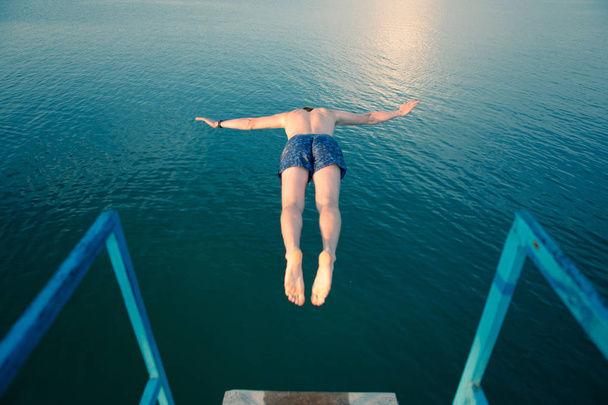 człowiek skoki z wieży na jeziorze wody na zachodzie słońca - Zdjęcie, obraz