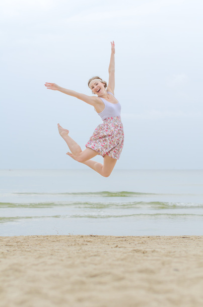 Young happy woman jumping on a sea shore - Zdjęcie, obraz