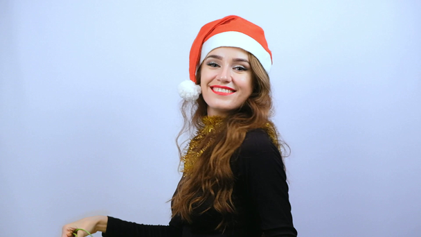 Mujer joven en vestido negro y sombrero rojo de Santa Claus sosteniendo coloridas bolsas de compras y sonriendo aislado sobre fondo blanco. Viernes Negro, Navidad o Año Nuevo concepto. Movimiento lento
. - Imágenes, Vídeo