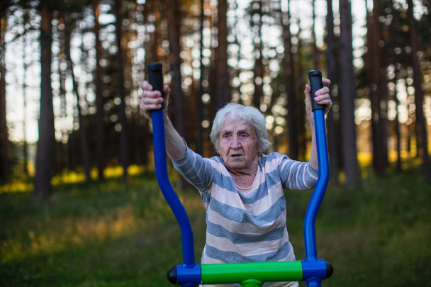 Bejaarde vrouw doen oefening op de speelplaats van de straat sport.  - Foto, afbeelding