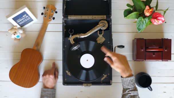 Lähikuva vinyyli levy pyörii vintage gramofoni valkoisessa pöydässä. Top näkymä miesten käsissä osoittaa nautintoa klassisen musiikin. Tunnistamaton mies kuuntelemassa ja nauttimassa levystä. Hidastus
 - Materiaali, video
