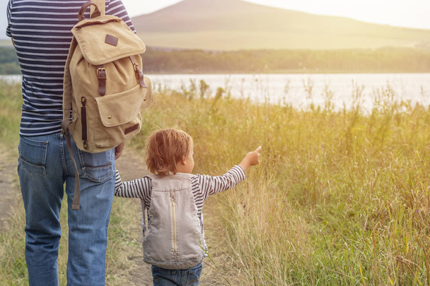 Father's day. Happy family: father and son travel together as tourists carry backpacks, go camping, relax, travel. Father and son have fun and play in nature - Foto, Bild
