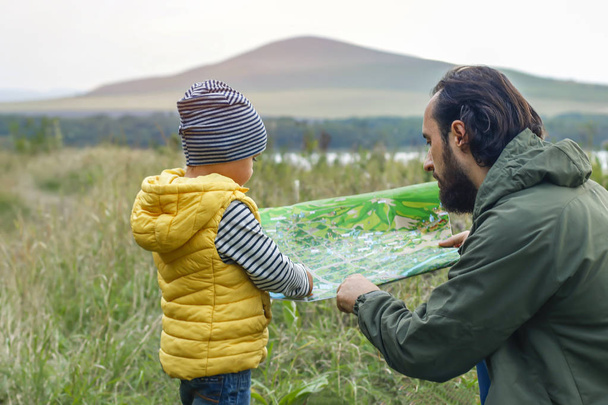 Onnellinen perhe lomalla, telttailemassa, lähdössä matkalle. Isä ja poika katsovat karttaa ja haluavat vuorille, luontoon. onnellinen ja harmoninen perhe ulkona syksyllä, keväällä. Isänpäivä
 - Valokuva, kuva
