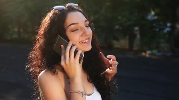 beautiful young smiling girl talking on the phone and straightens her hair - Filmati, video