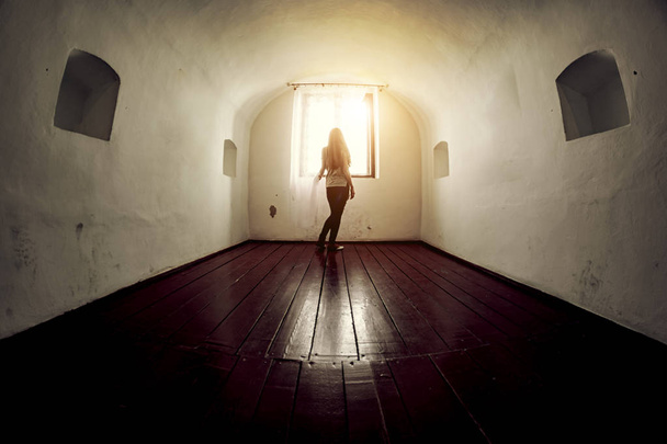 Дівчина стоїть біля вікна в кімнаті старої фортеці. Замок Паланок-одна з найстаріших українських фортець в Мукачево - Фото, зображення