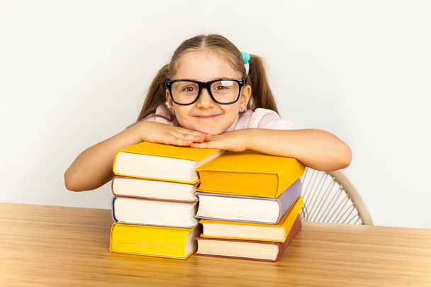 улыбающаяся маленькая студентка со многими книгами в школе
 - Фото, изображение