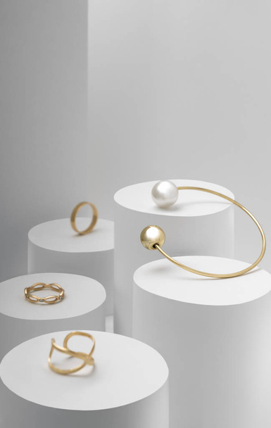 Gouden parel armband met gouden ringen collectie op witte cilinders - Foto, afbeelding