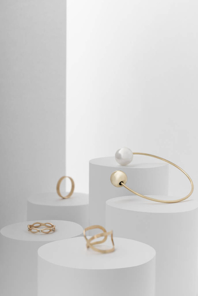 Bijoux dorés, bracelet et différentes bagues dorées sur fond blanc
 - Photo, image
