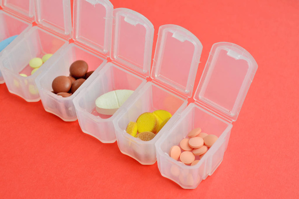 Plastic daily organizer for pills, box with different pills on pink background with copyspace - Fotoğraf, Görsel