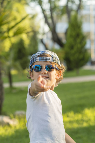 Portrait of a boy with cap and sunglasses gesturing. - Fotografie, Obrázek