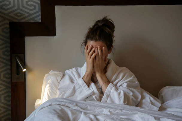 junge traurige Frau, die im Bett sitzt, Depressionen, Angstzustände, Beziehungsschwierigkeiten, Migräne oder Morgenübelkeit - Foto, Bild