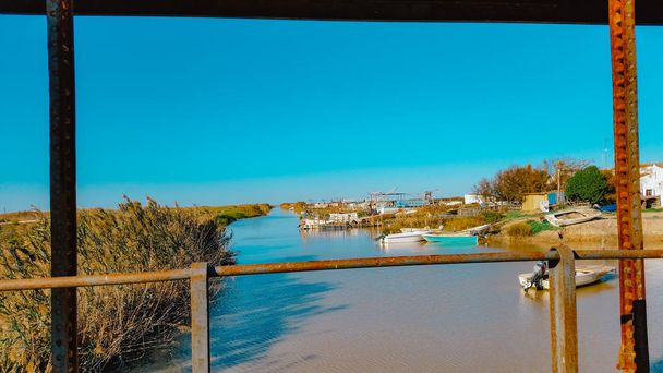 стоя на мосту, наблюдая за рекой с лодками. над потоком воды с баржами
 - Фото, изображение