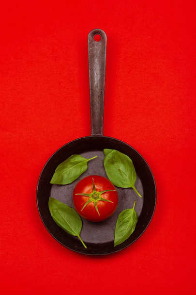 Fresh tomato on frying pan with basilic. - Zdjęcie, obraz