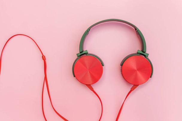 Czerwone słuchawki z przewodem izolowanym na różowo-pastelowe kolorowe tło - Zdjęcie, obraz