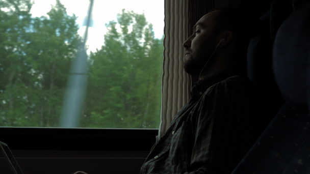 Homme avec écouteurs dans le train regardant par la fenêtre. - Séquence, vidéo