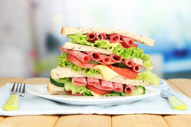 Huge sandwich on wooden table, on bright background - Valokuva, kuva